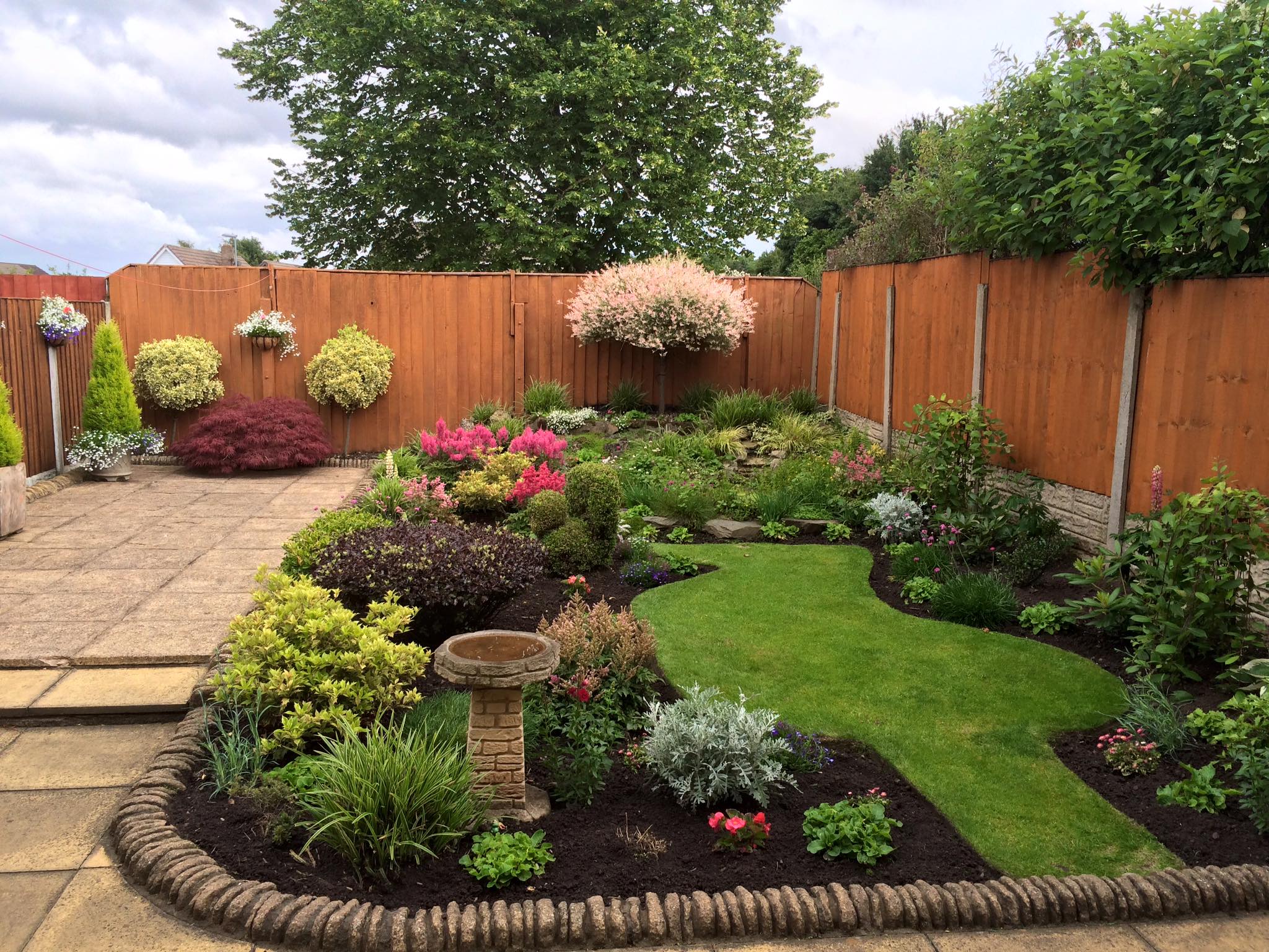 A Merseyside back garden maintained by JL Garden Services - shaped borders, cut lawn and feather-edge fencing.